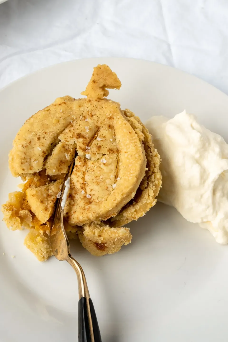 Pumpkin-shaped apple pie with whipped cream on white plate