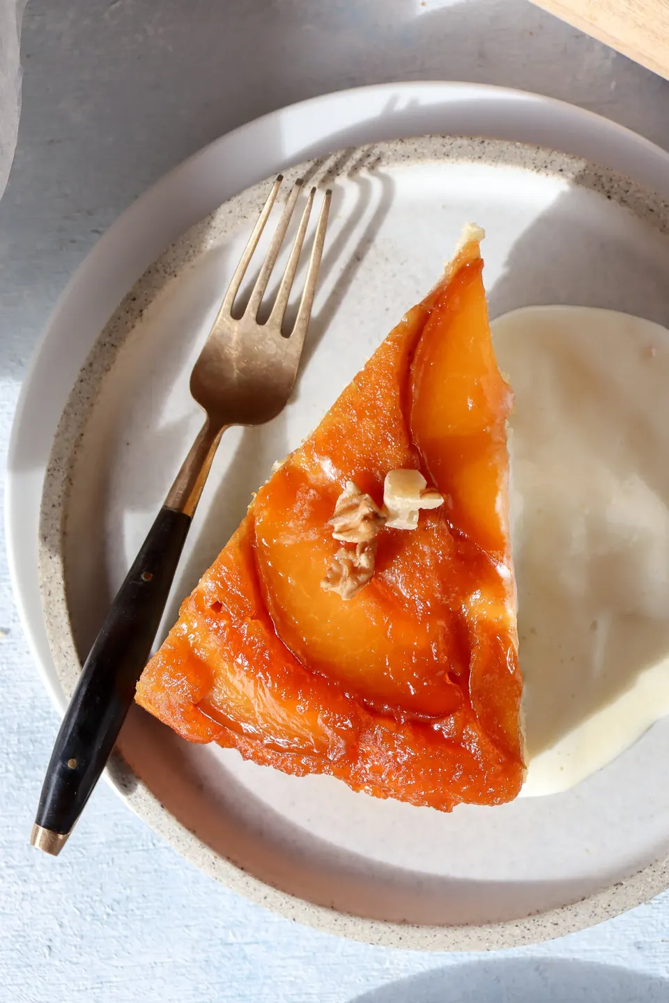 Slice of maple peach tarte tatin cake with cream and fork