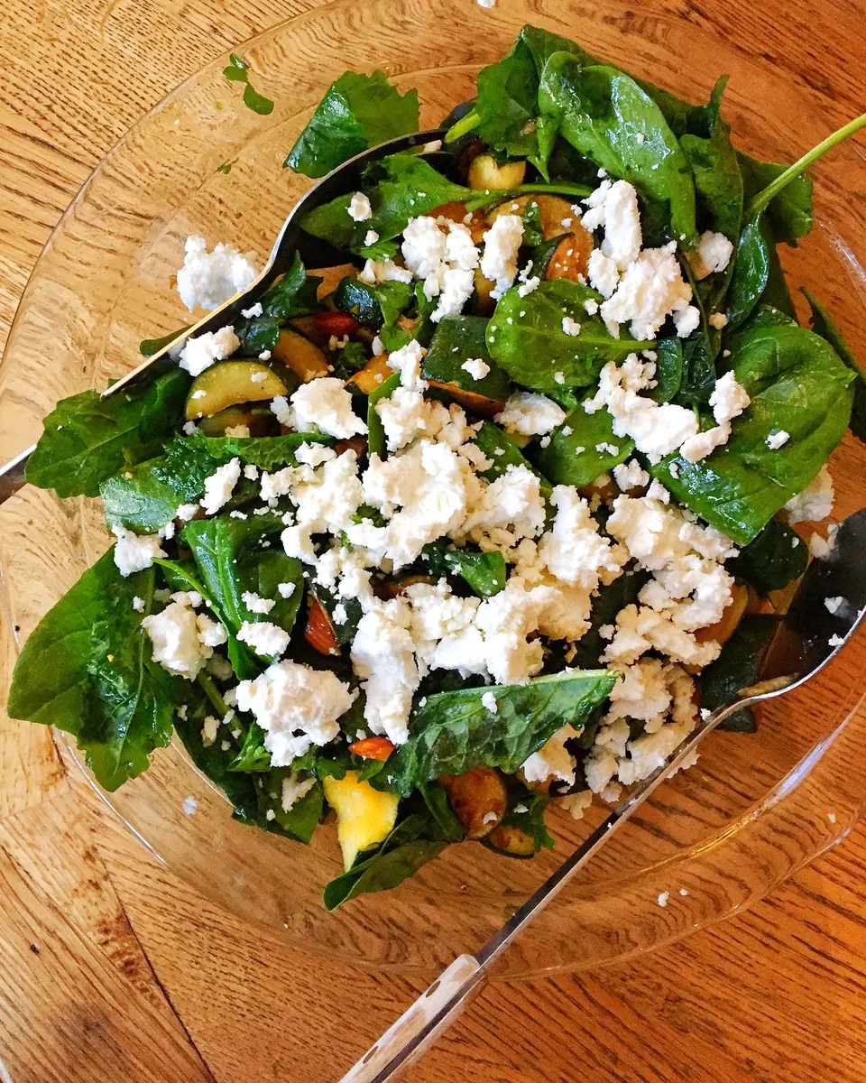 Spinach and zucchini salad topped with crumbled goat cheese