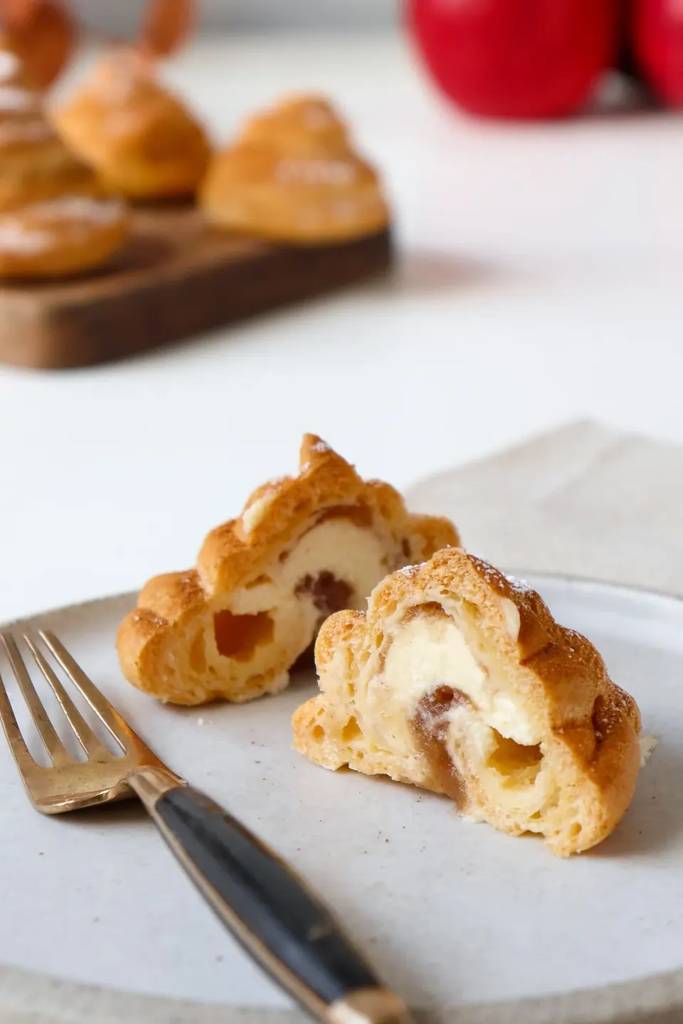 Cut apple-spiced profiteroles with cream filling on a white plate