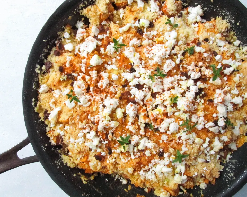 Skillet sweet potato crumble topped with goat cheese and herbs