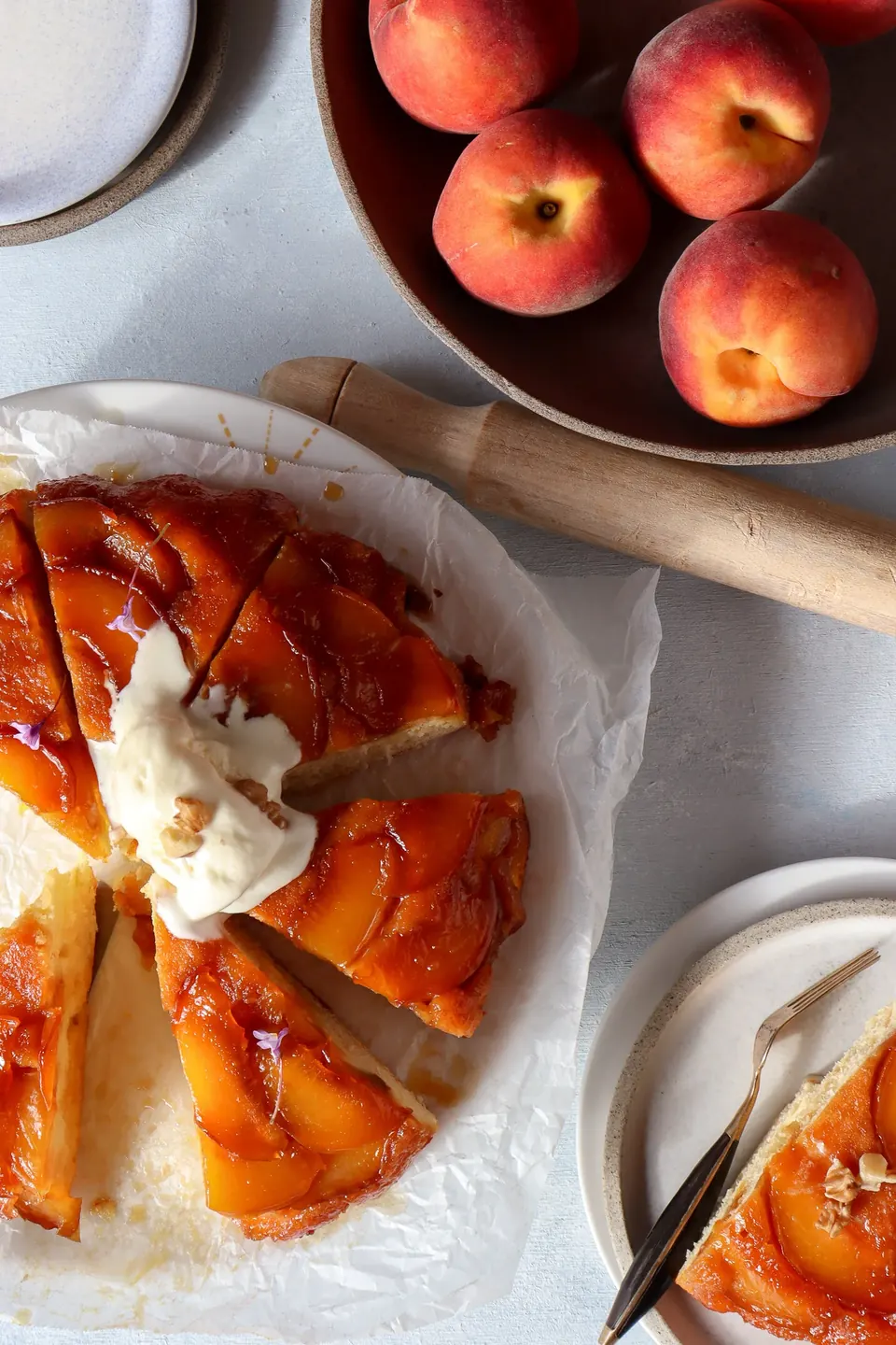 Sliced peach tarte tatin cake with cream beside fresh peaches