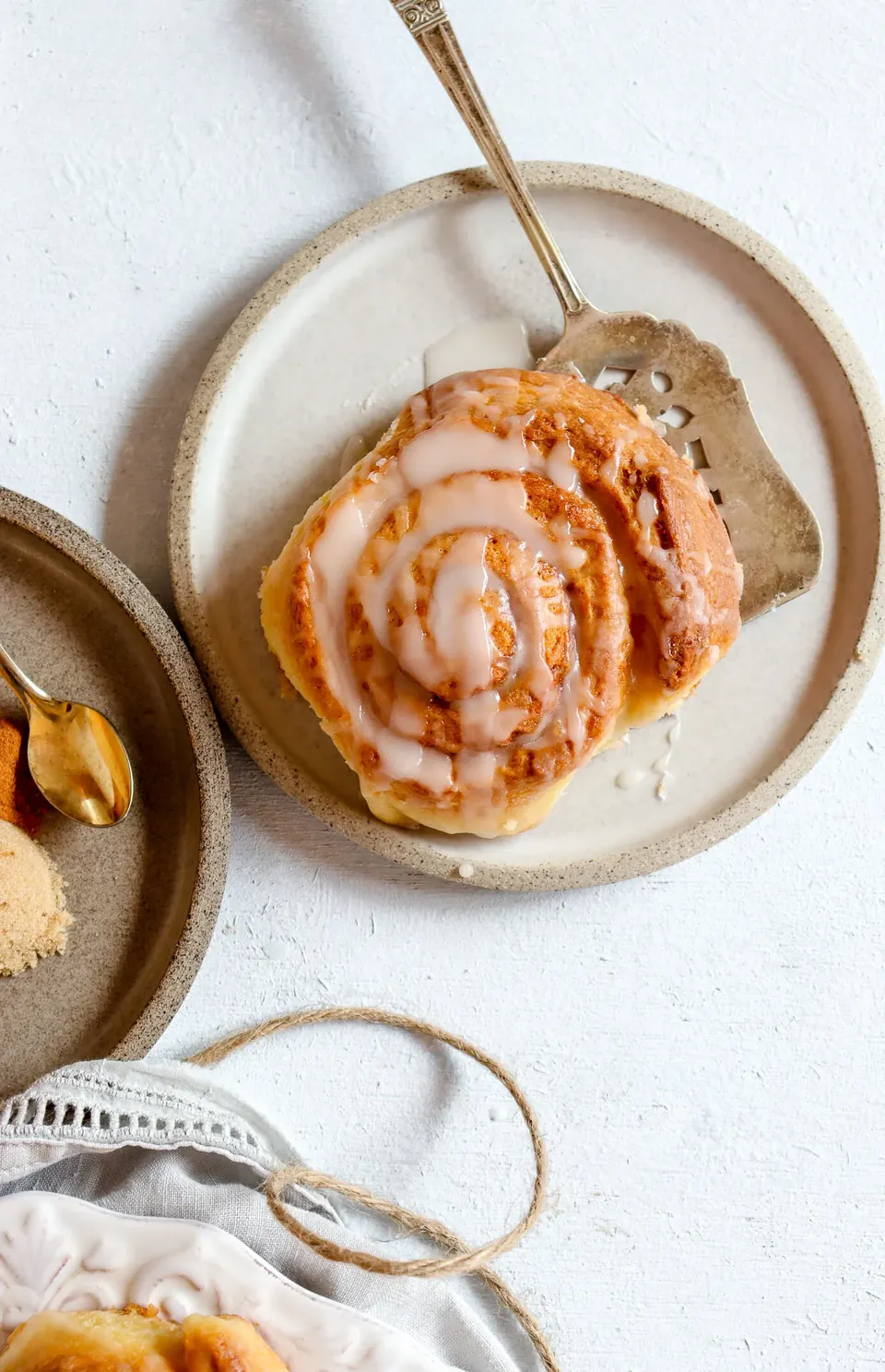 Glazed cinnamon roll on ceramic plate with vintage metal server