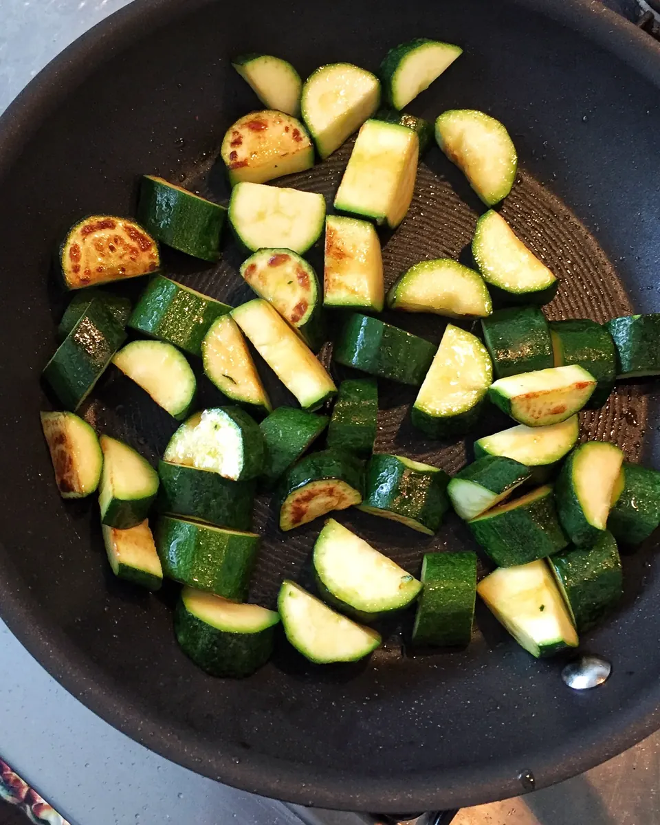 Browned zucchini chunks cooking in a nonstick skillet