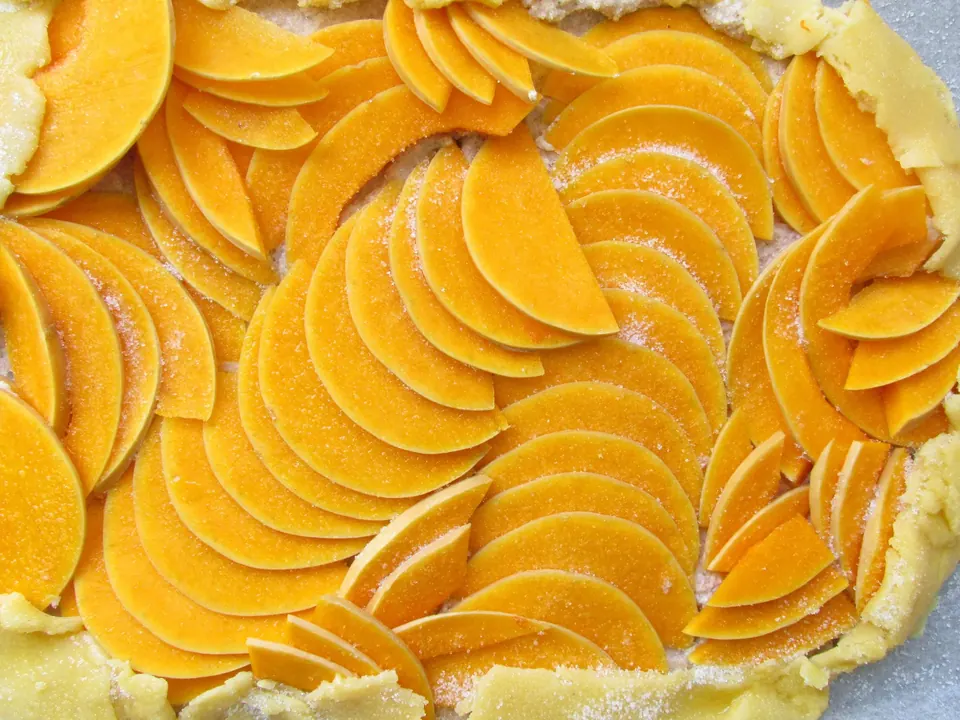Thinly sliced pumpkin layered over galette crust with sugar