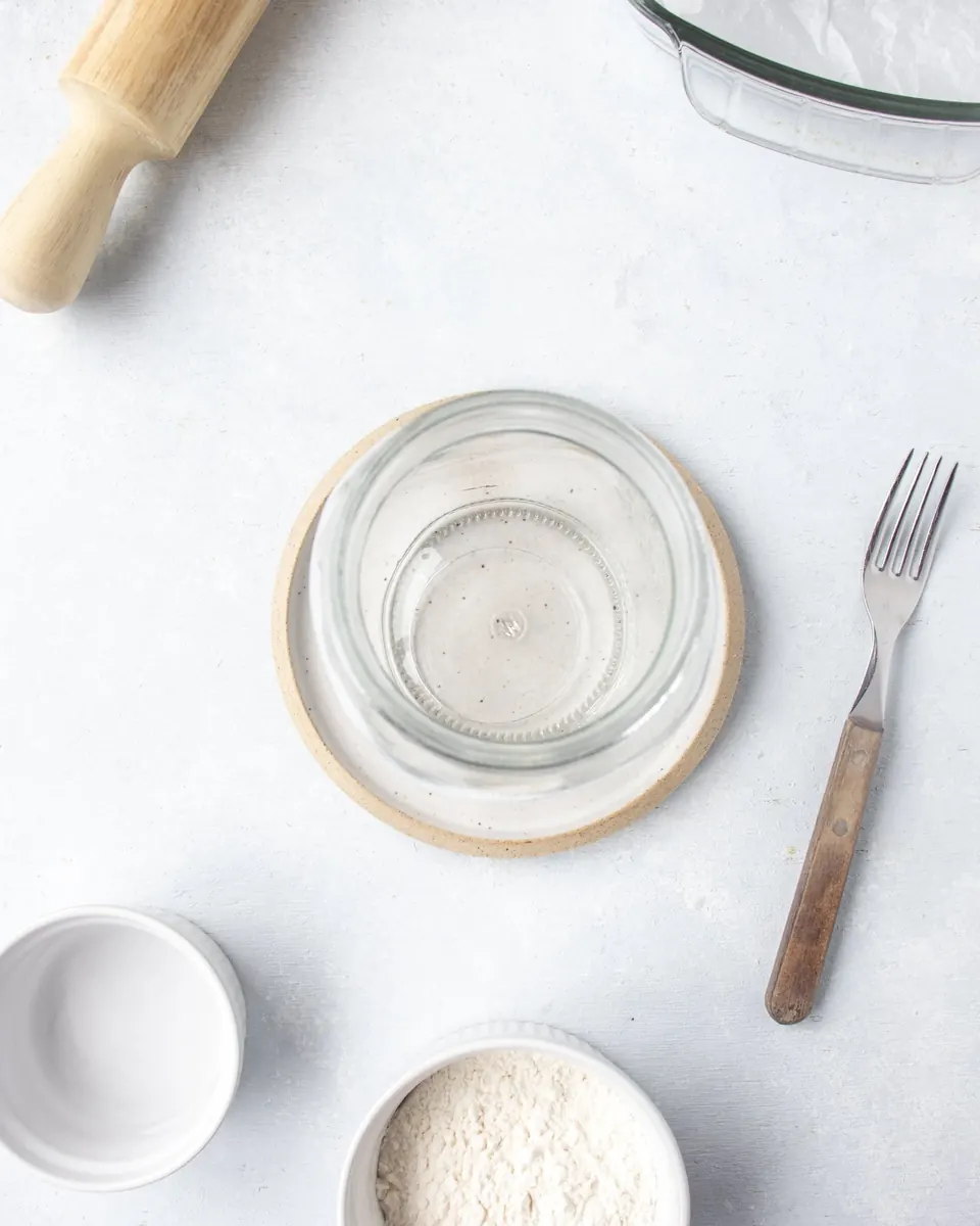 Empty glass jar with flour bowls, rolling pin, and fork