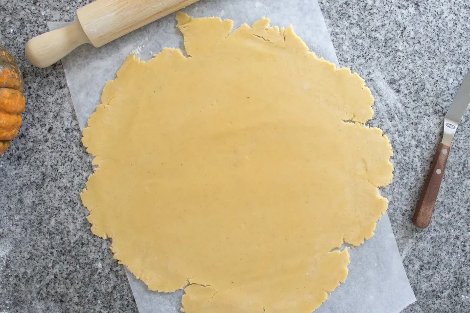 Rolled pie dough on parchment with rolling pin and knife