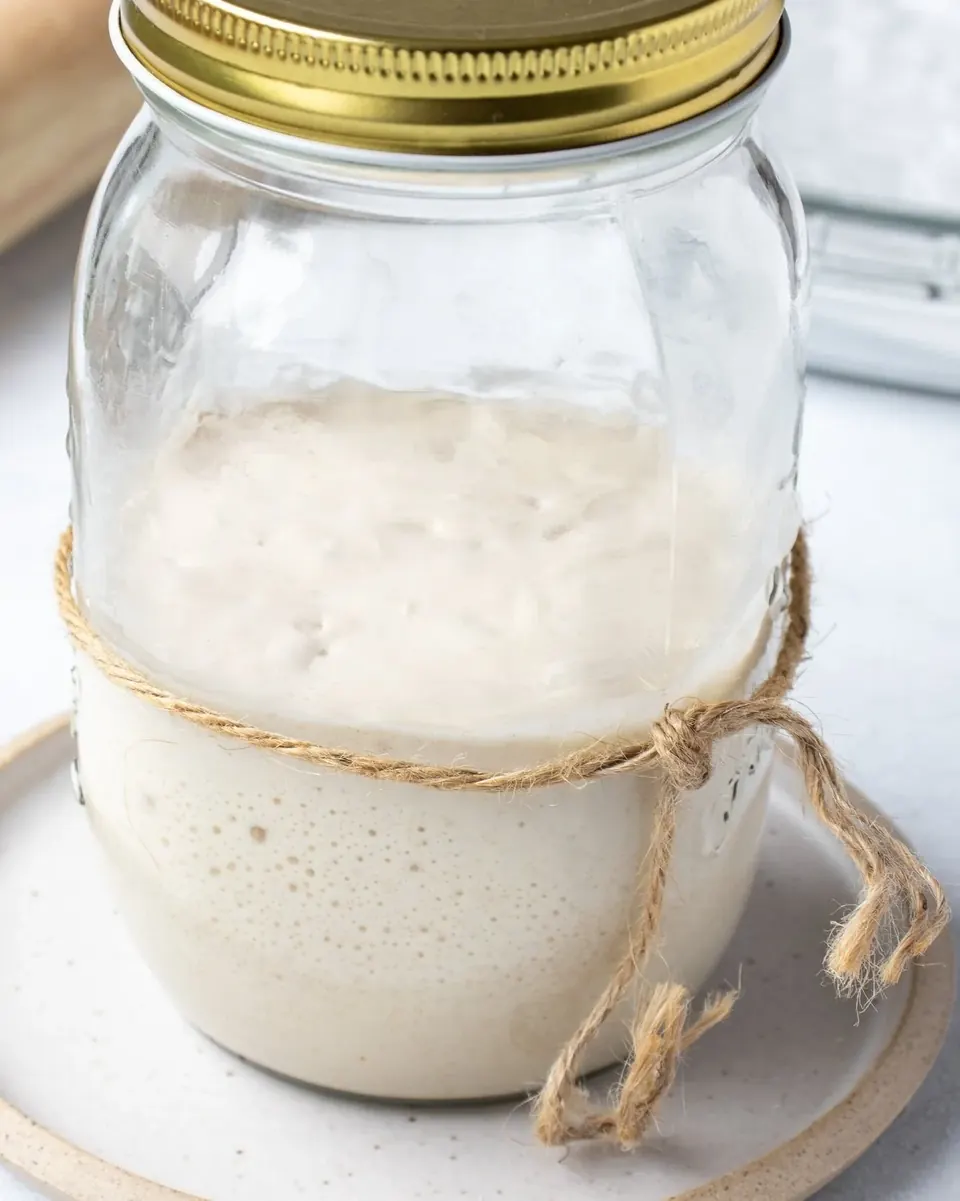 Jar of bubbly sourdough starter tied with twine