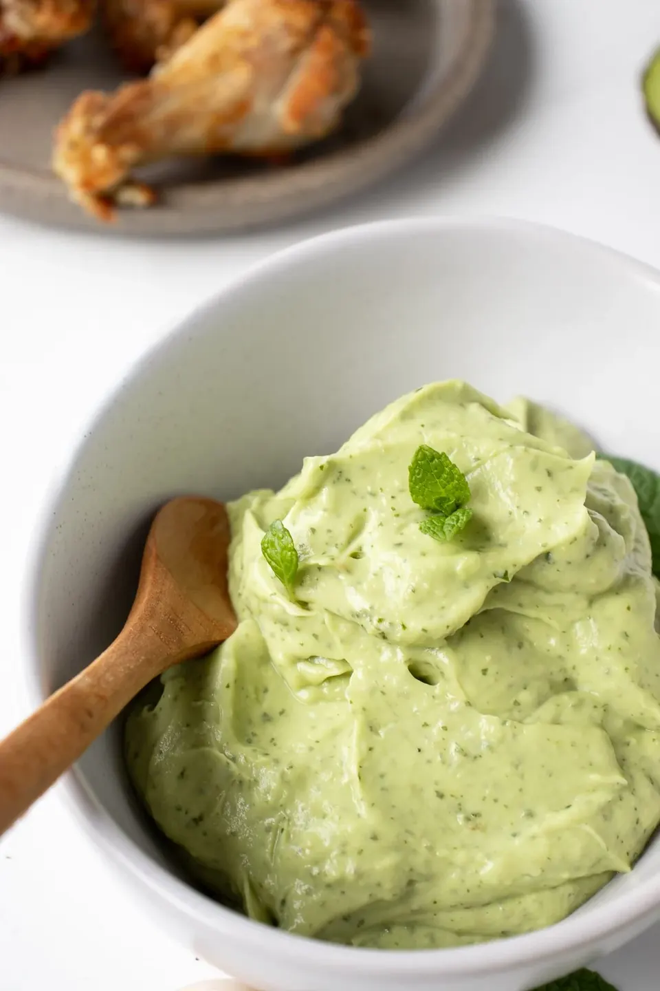 Creamy avocado mint dip in a white bowl with spoon