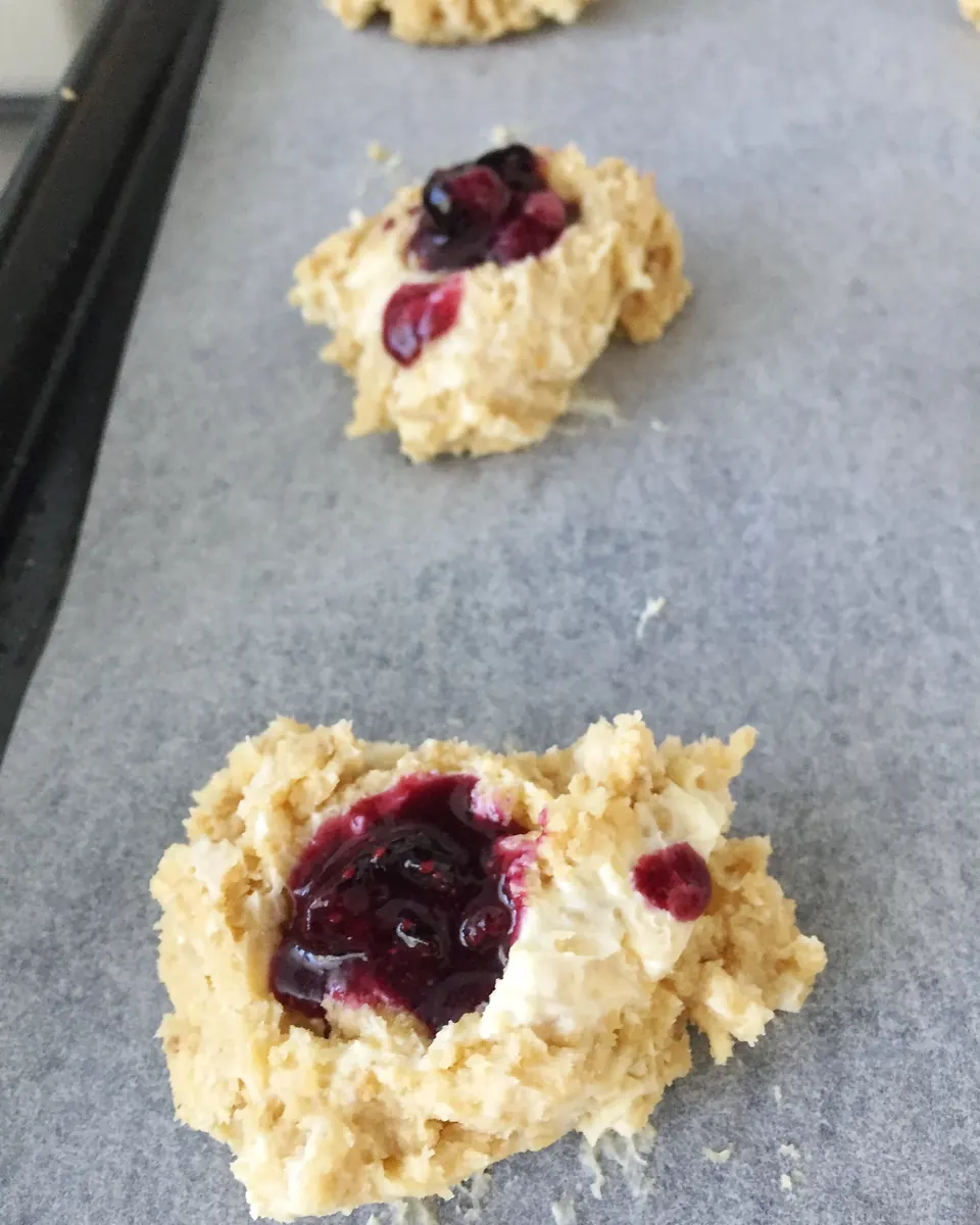 Blueberry cream cheese cookie dough scoops on a parchment-lined baking sheet