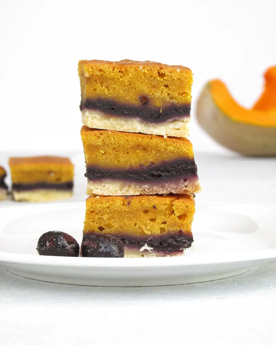 Stacked pumpkin blueberry pie bars on a white plate
