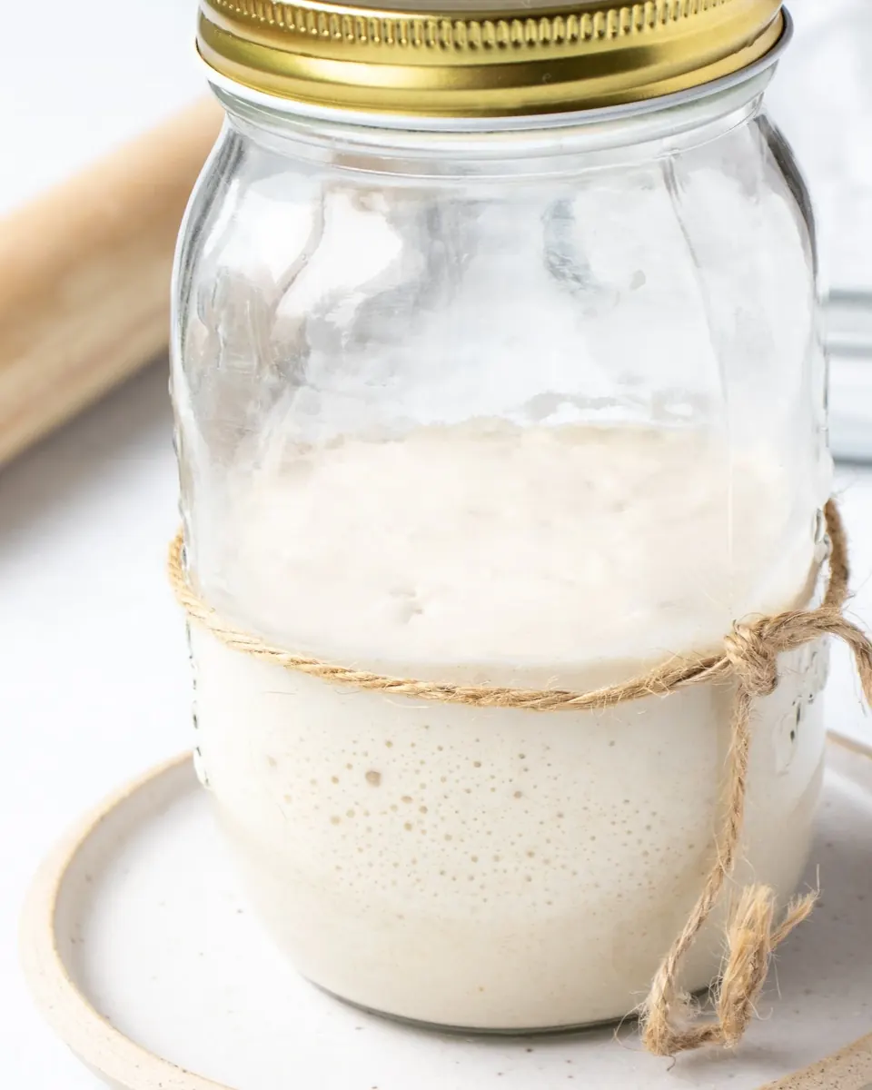 Jar of bubbly sourdough starter tied with twine