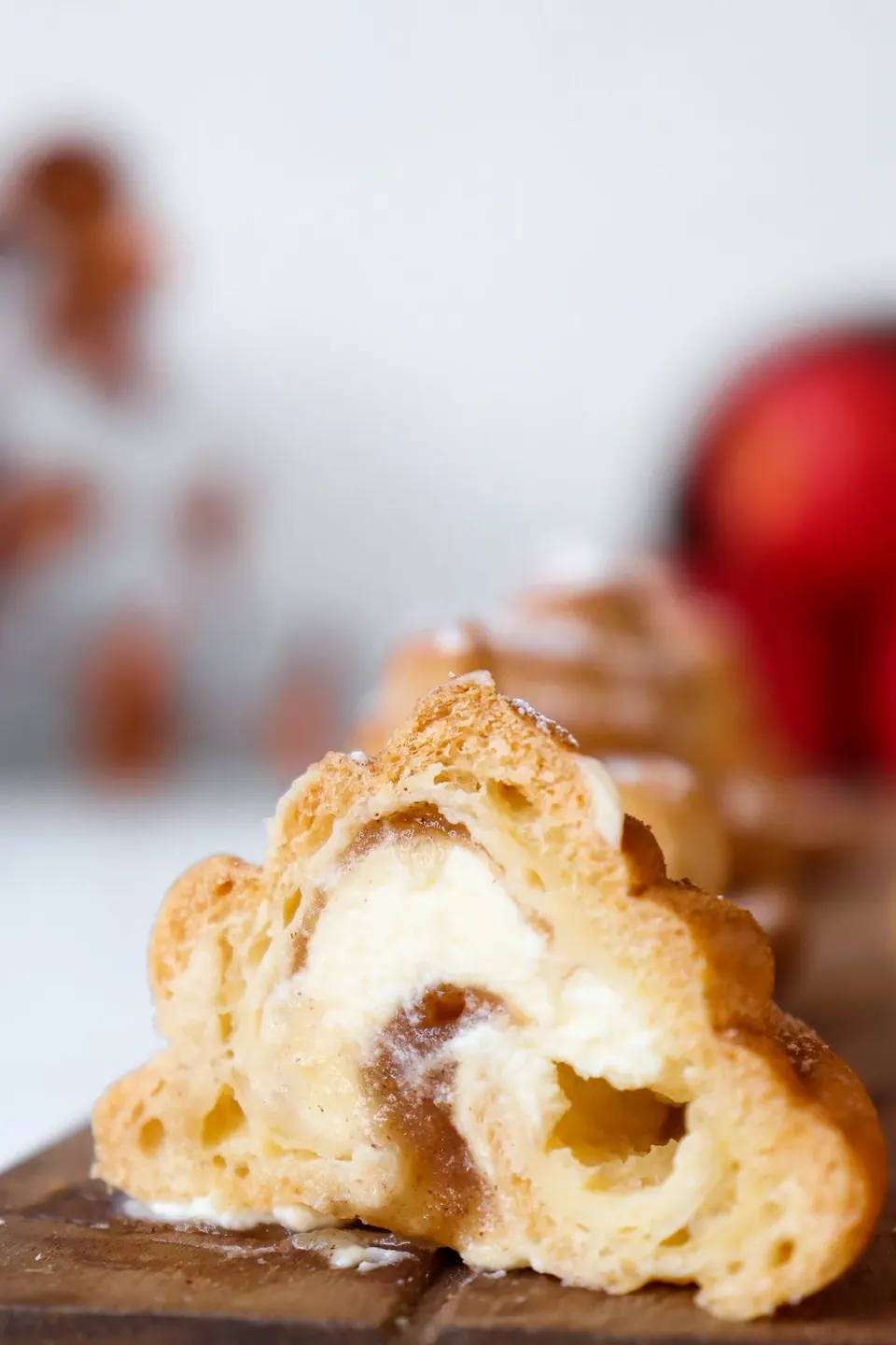 Cut apple-spiced profiterole with cream filling on wooden board