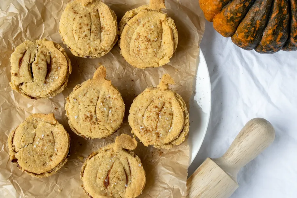 Mini pumpkin pies on parchment with a decorative gourd