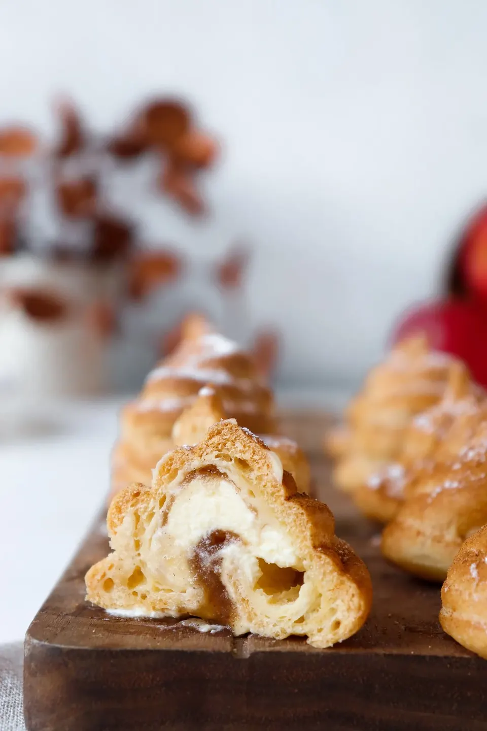 Cut apple spiced profiterole with creamy filling on wooden board