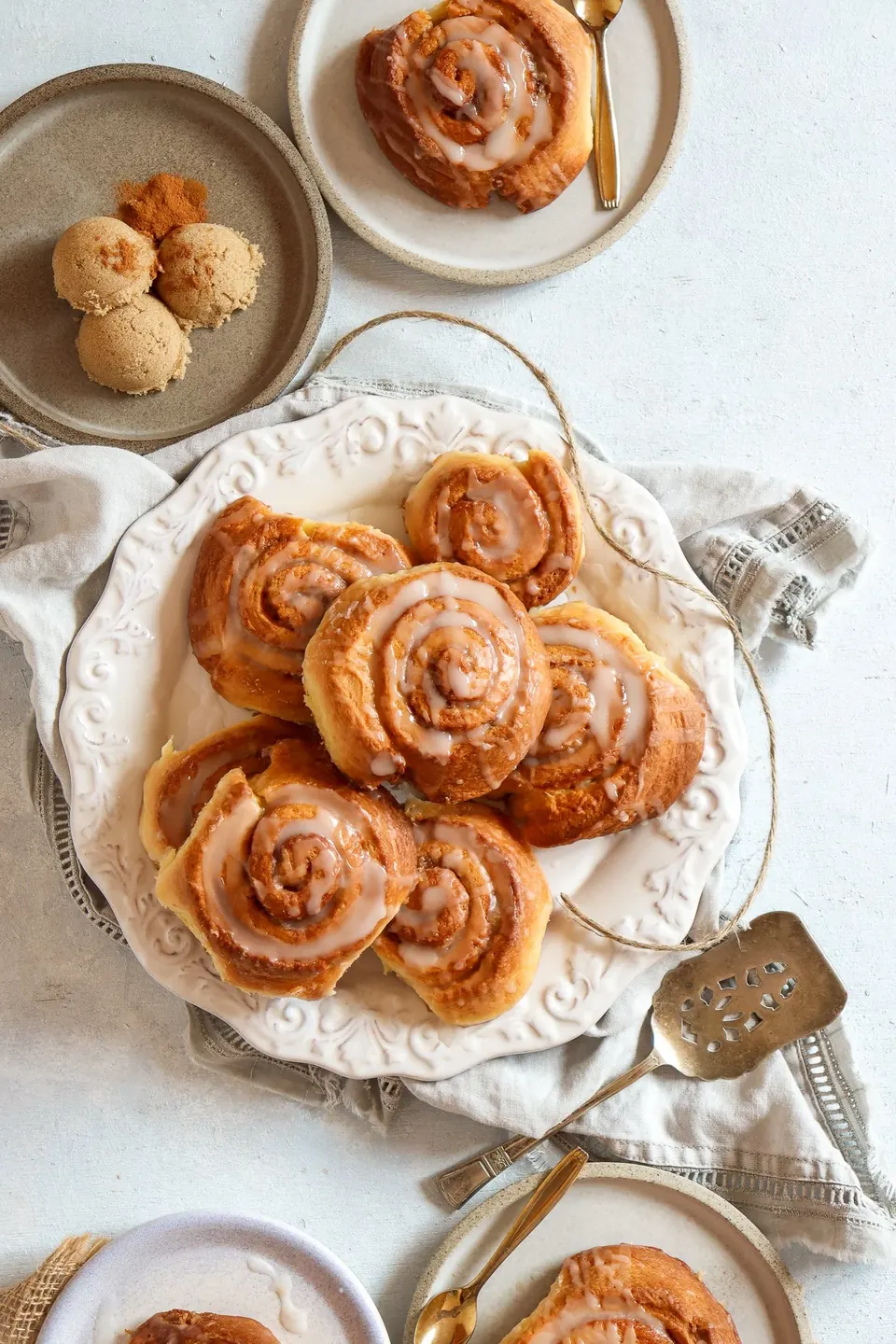 Glazed cinnamon rolls on a platter with brown sugar scoops
