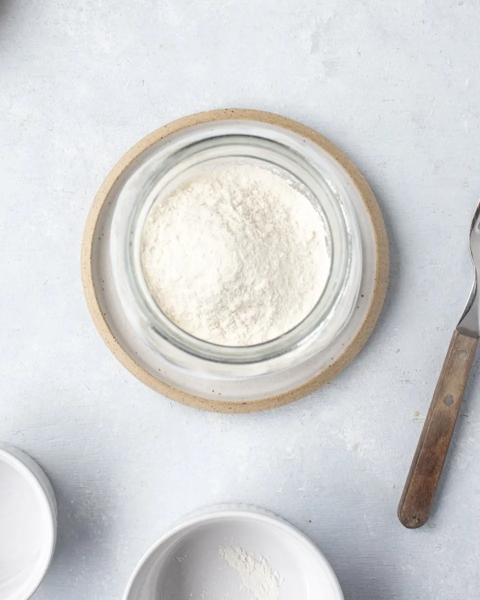 Overhead view of flour in a glass jar and bowls